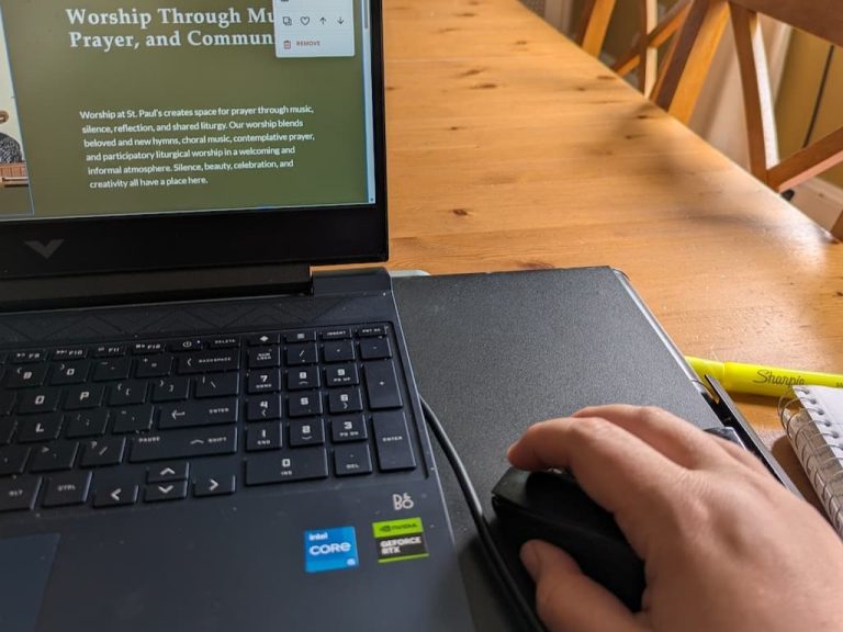 designing a local business website on a laptop screen with a hand on the mouse